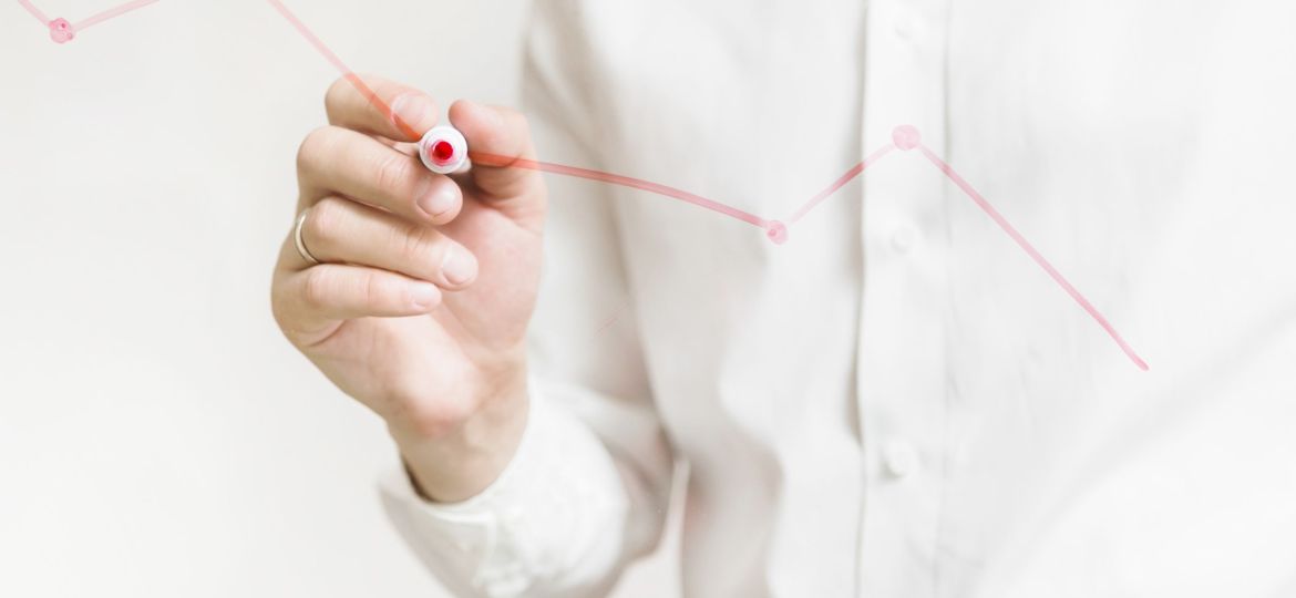 businessperson-s-hand-preparing-red-graph-glass-board