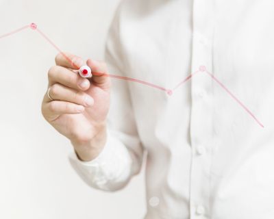 businessperson-s-hand-preparing-red-graph-glass-board