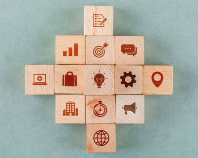 Business strategy concept with wooden blocks with icons on sage color background flat lay. horizontal image