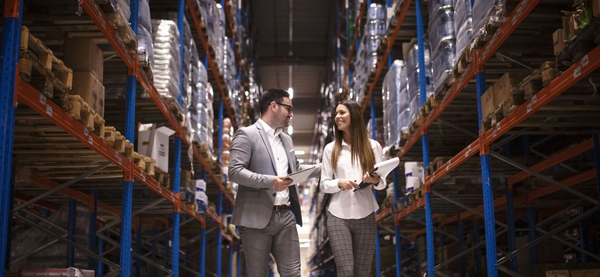 Business people walking through large distribution center and talking about increasing production and organization.